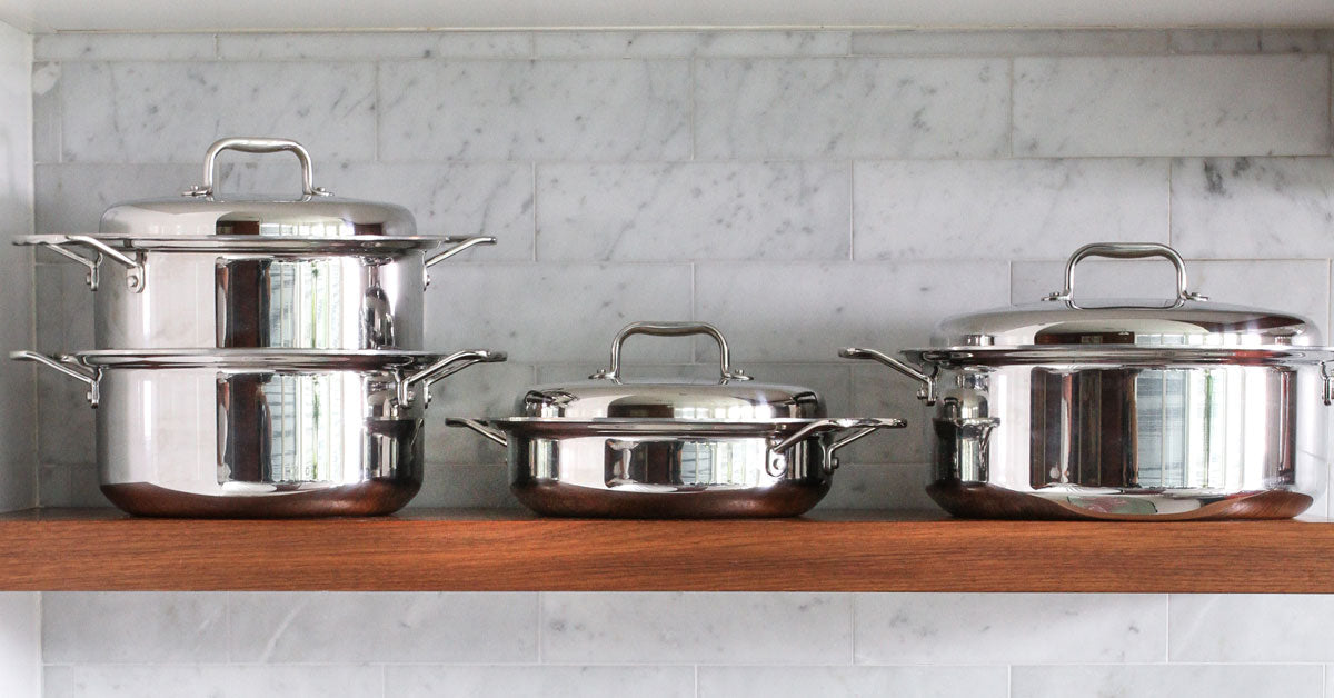 Three pieces of stainless steel 360cookwares on a wooden shelf, showcasing their design and quality.