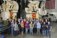 Group photo of 360cookwares team in manufacturing facility with machinery in background