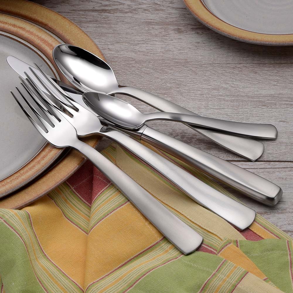 Satin America 45 Piece Set flatware displayed on a table with plates and a colorful napkin