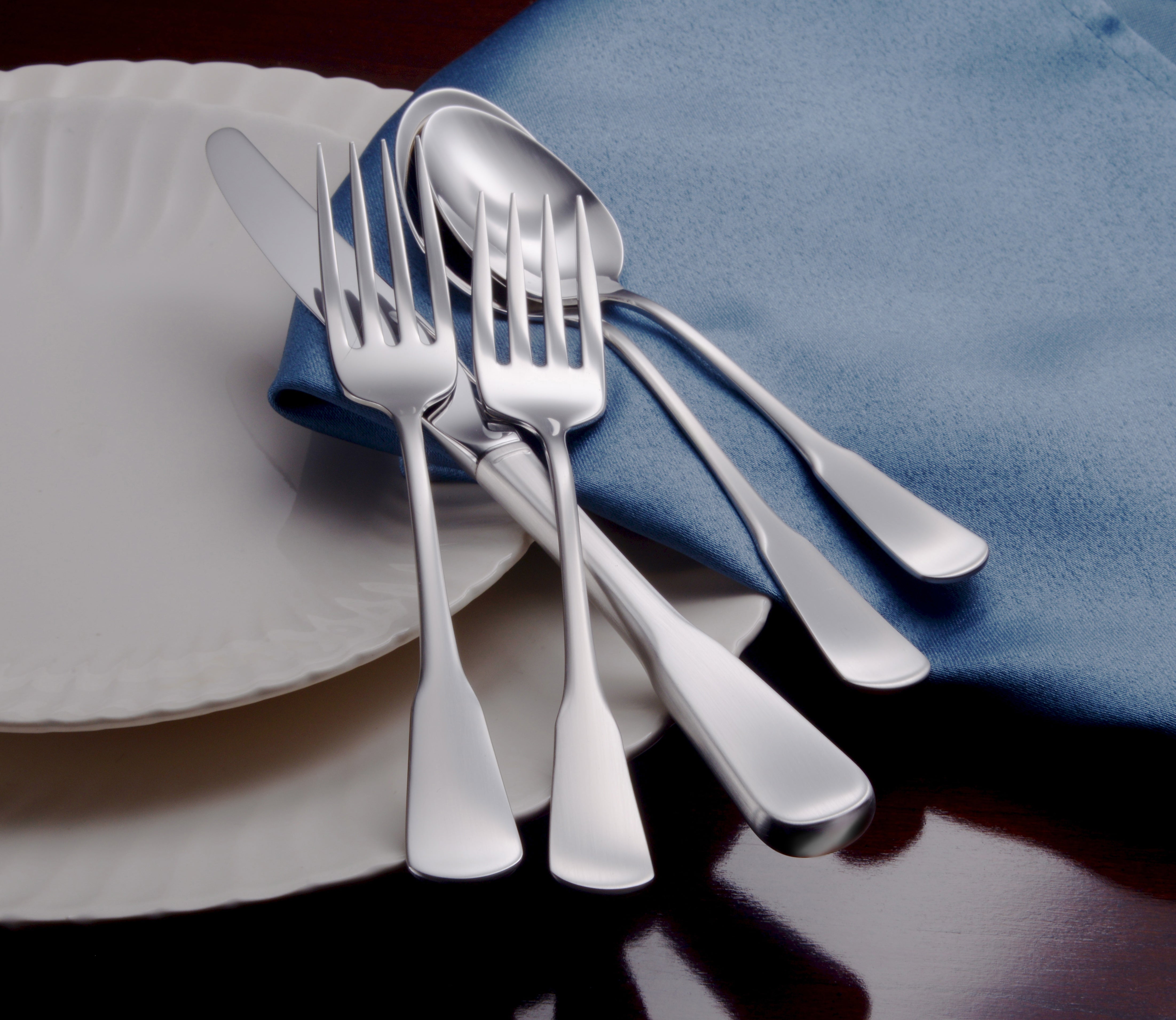 Candra 45 Piece Flatware Set on a blue napkin with a plate