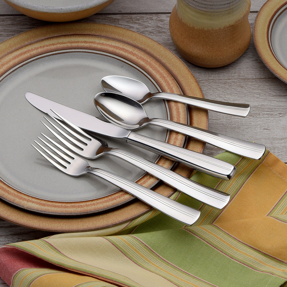 Cedarcrest 65 Piece Flatware Set displayed on plates with a colorful napkin