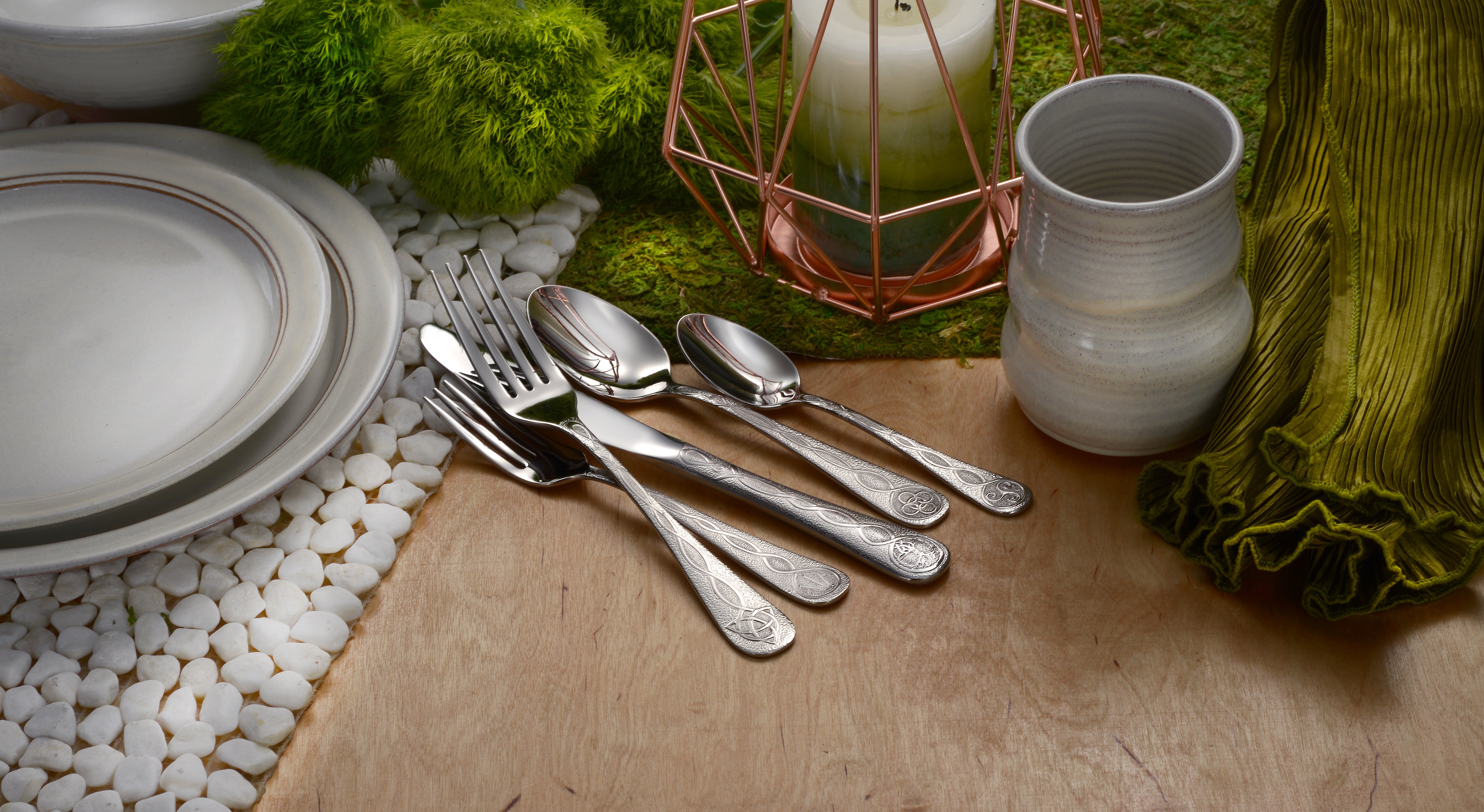 Celtic 65 Piece Flatware Set displayed on a table with plates and decor