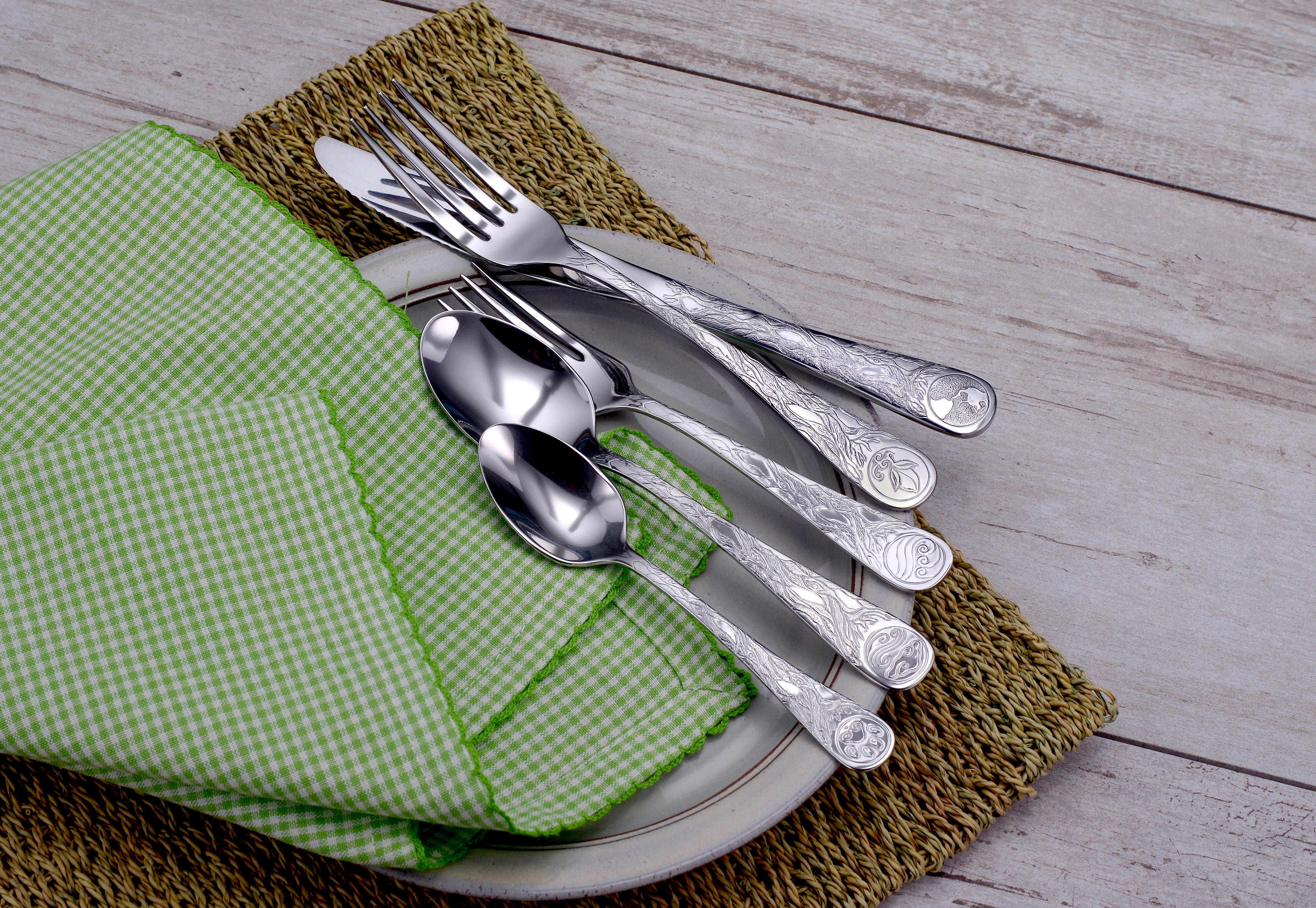 Earth Pattern Flatware set displayed on a plate with a green checkered napkin and woven placemat.