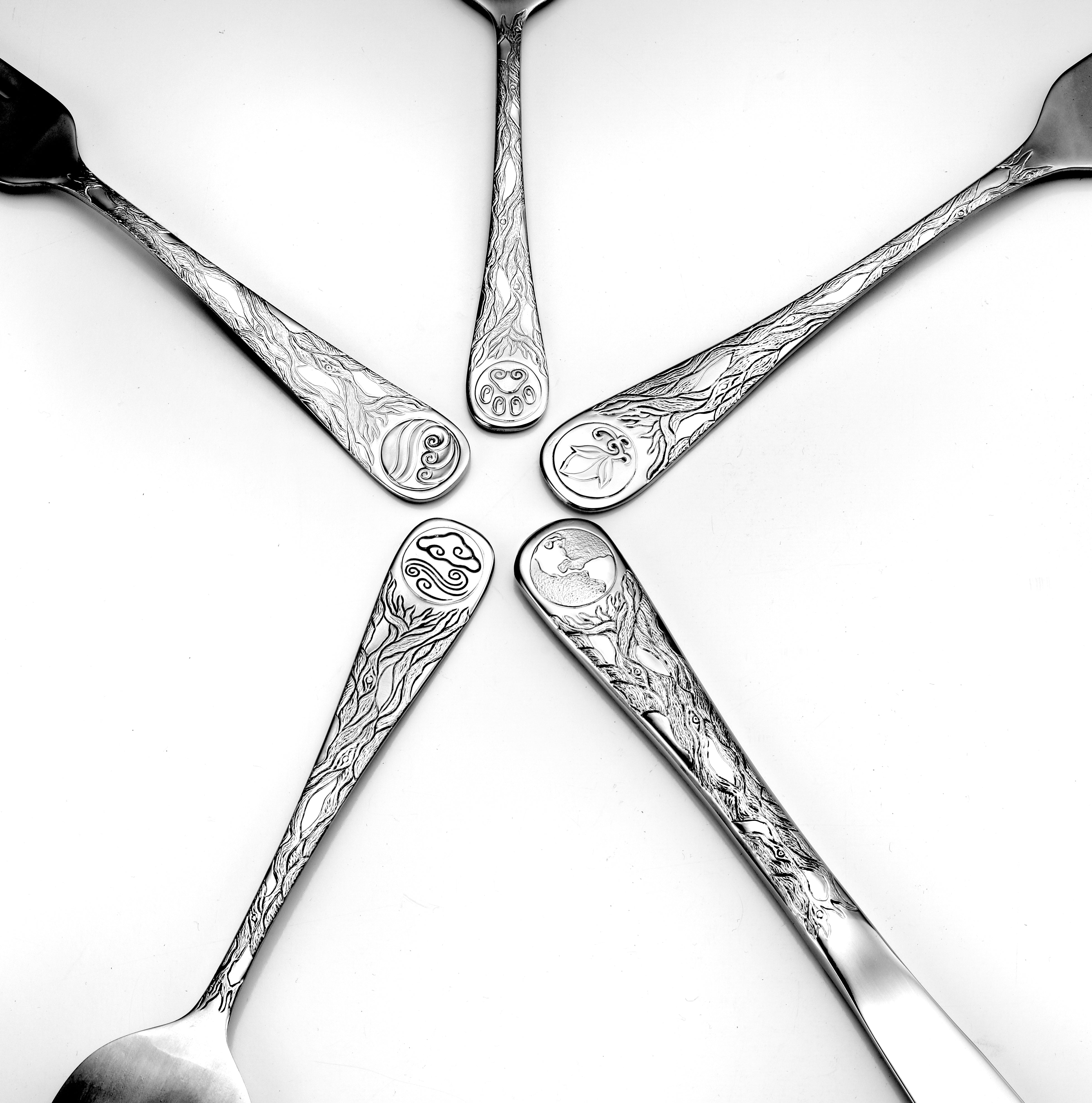 Five pieces of flatware featuring intricate designs representing Earth and nature.