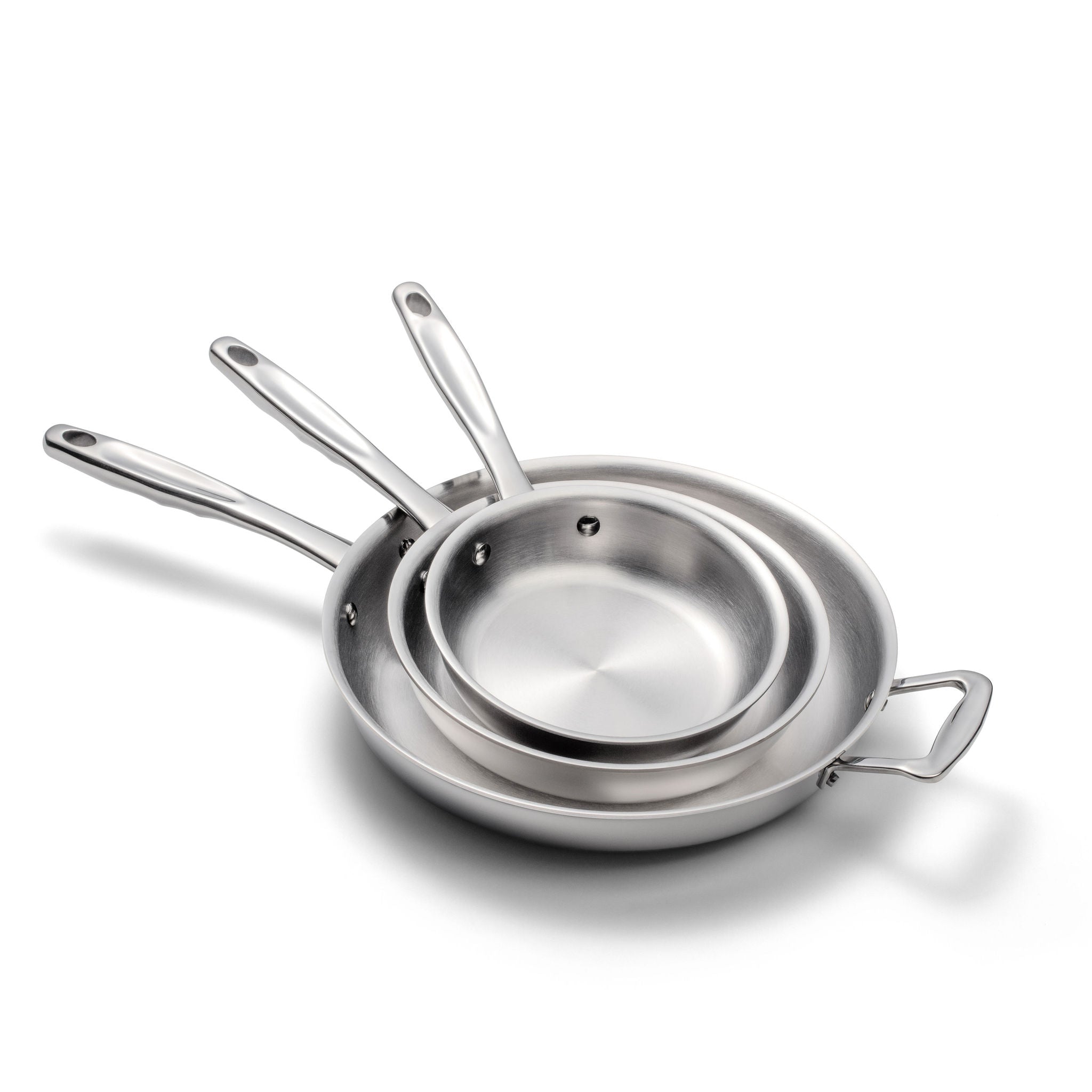 Three nested polished stainless-steel frying pans with long handles and a looped side handle, arranged on white background.