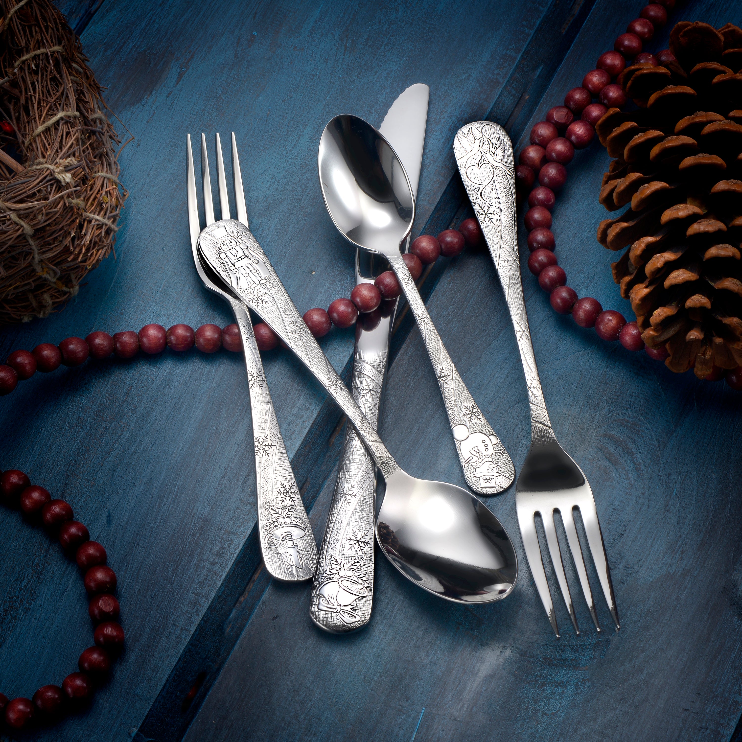 Five pieces of decorative flatware with intricate designs on handles, set against a festive background.