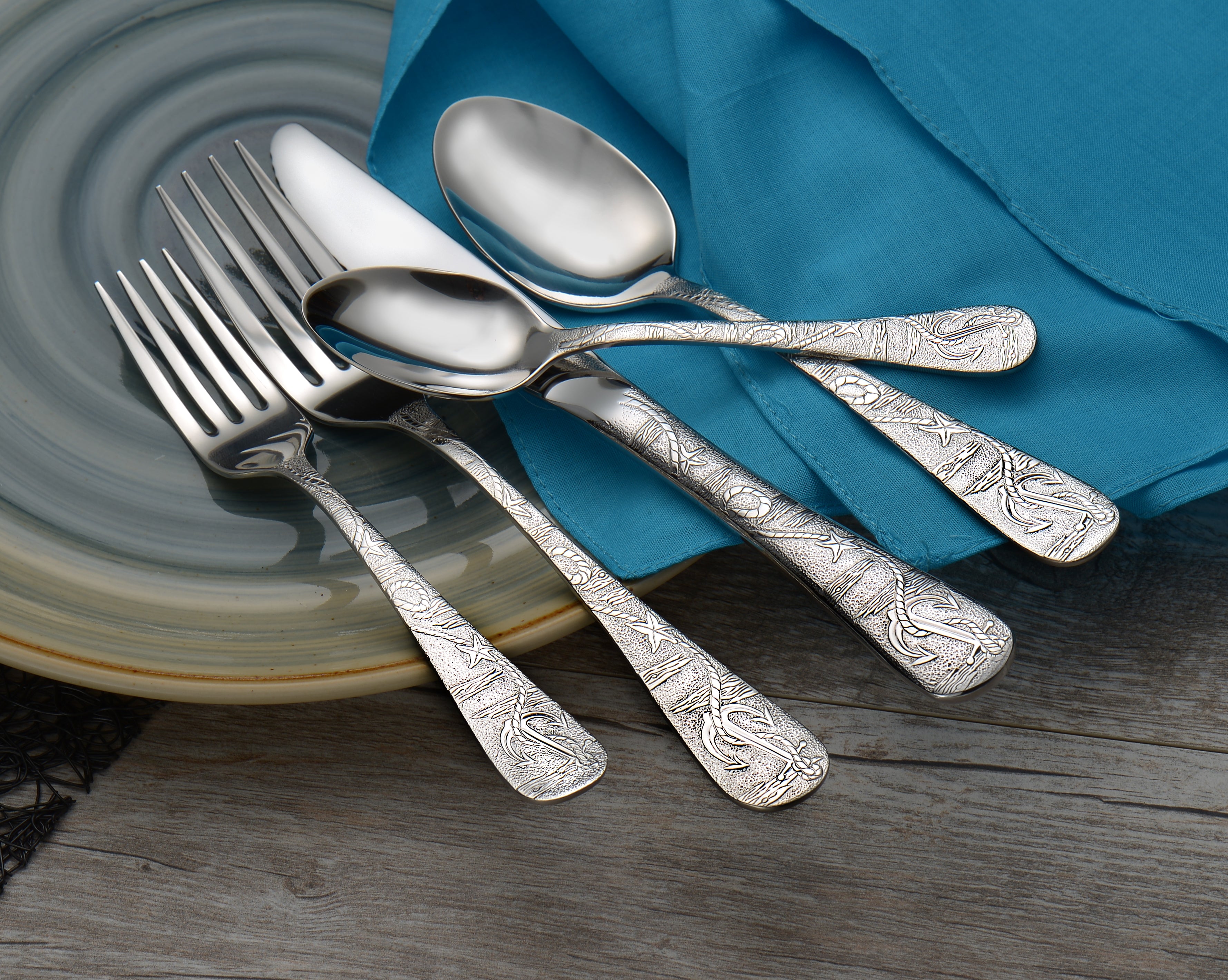 Old Harbor 65 Piece Set featuring decorative silverware on a plate with a blue cloth