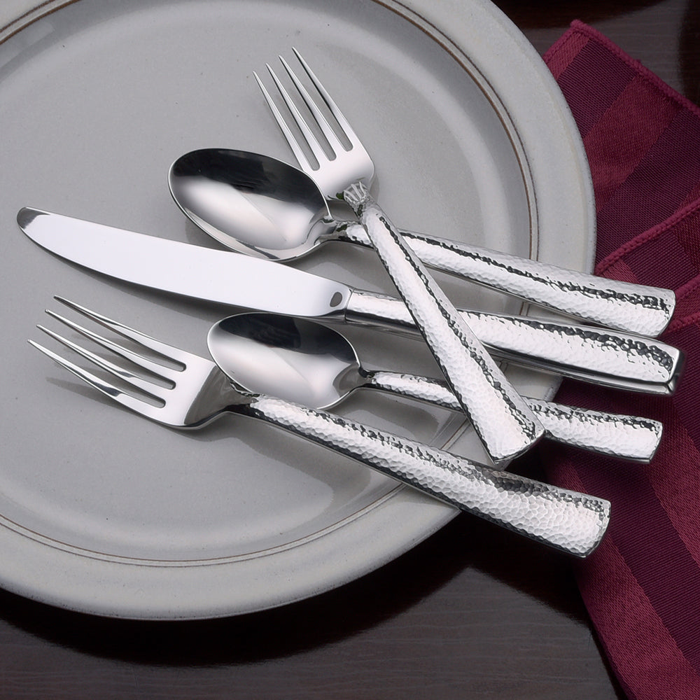 Pinehurst 65 Piece Set flatware displayed on a plate, including a knife, fork, and spoon.