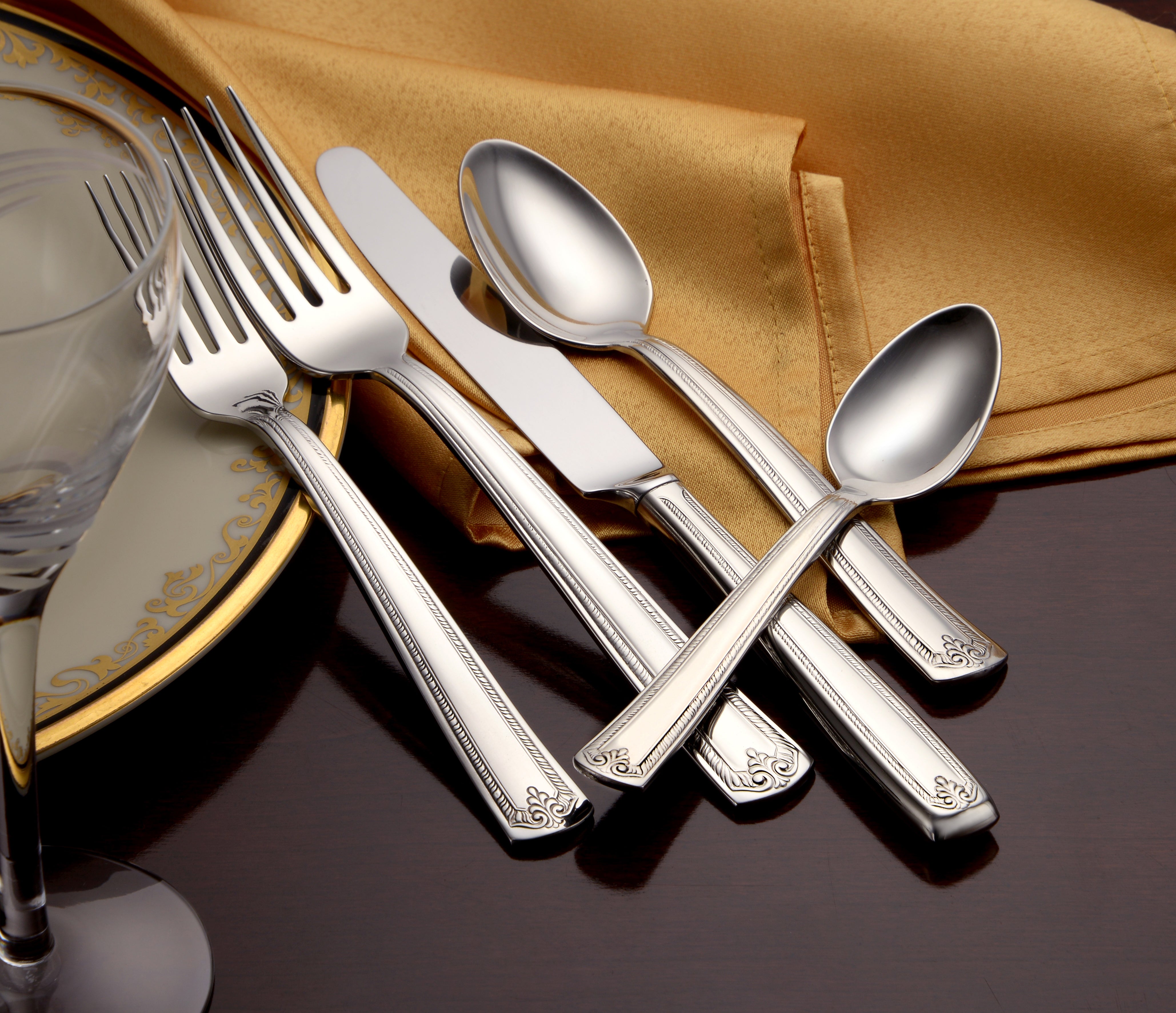 Five pieces of Prestige flatware including forks, spoons, and a knife on a table setting with a golden cloth.