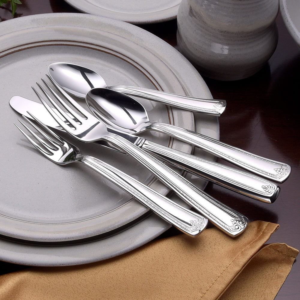 Four pieces of Prestige flatware on a plate with a napkin
